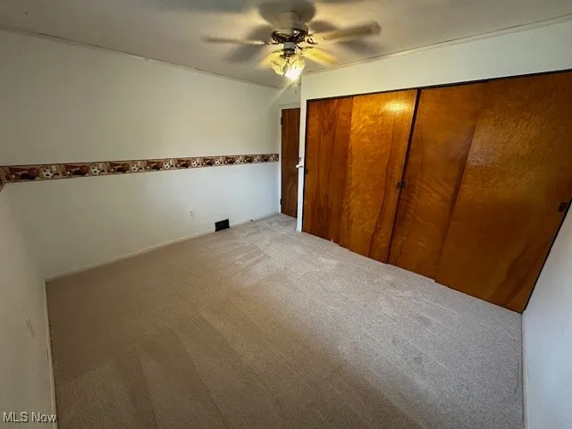 Unfurnished bedroom with a ceiling fan, carpet flooring, and a closet