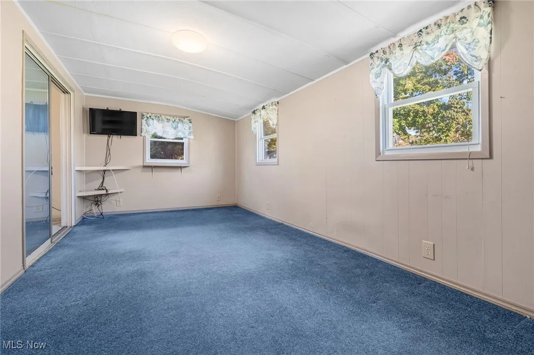 Empty room with carpet flooring and lofted ceiling