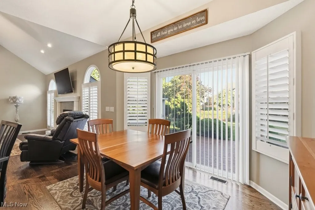 Dining area featuring lofted ceiling, dark wood-type flooring, recessed lighting, and a tiled fireplace