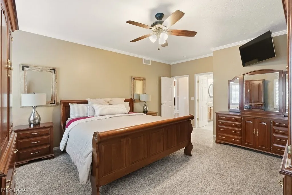 Bedroom featuring light colored carpet, ceiling fan, and ornamental molding