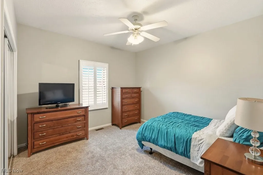 Bedroom with light carpet and a ceiling fan