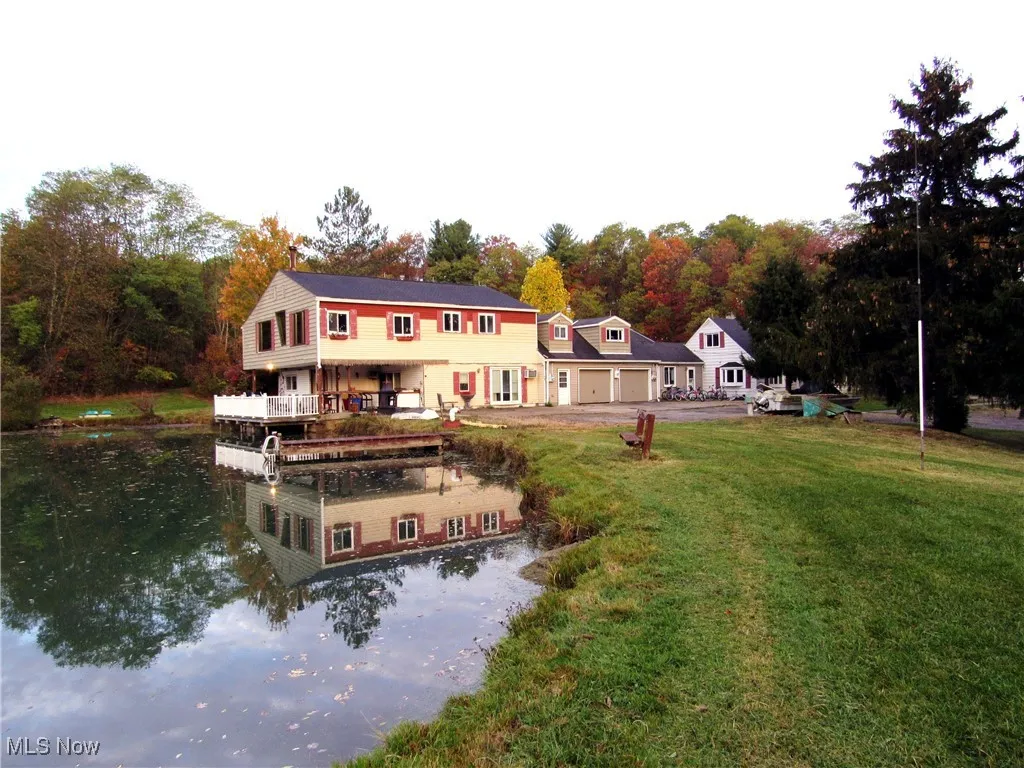 Rear view of property with a water view, a lawn, driveway, a balcony, and a garage