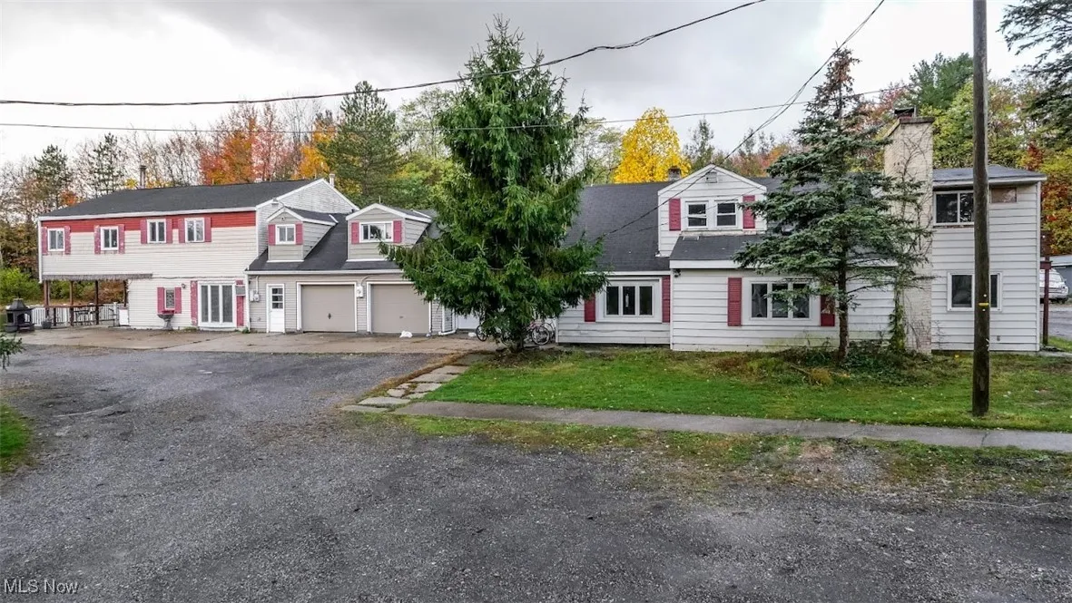 View of front of house featuring a chimney, a garage, and asphalt driveway
