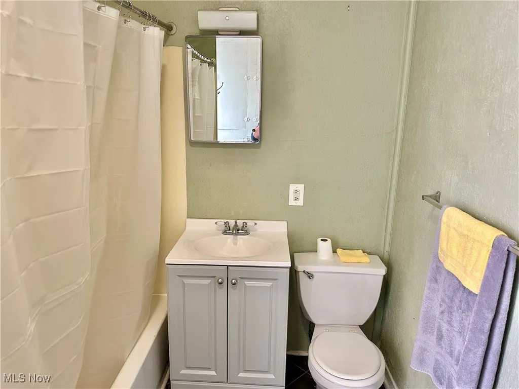 Bathroom with vanity, a textured wall, and shower / tub combo with curtain