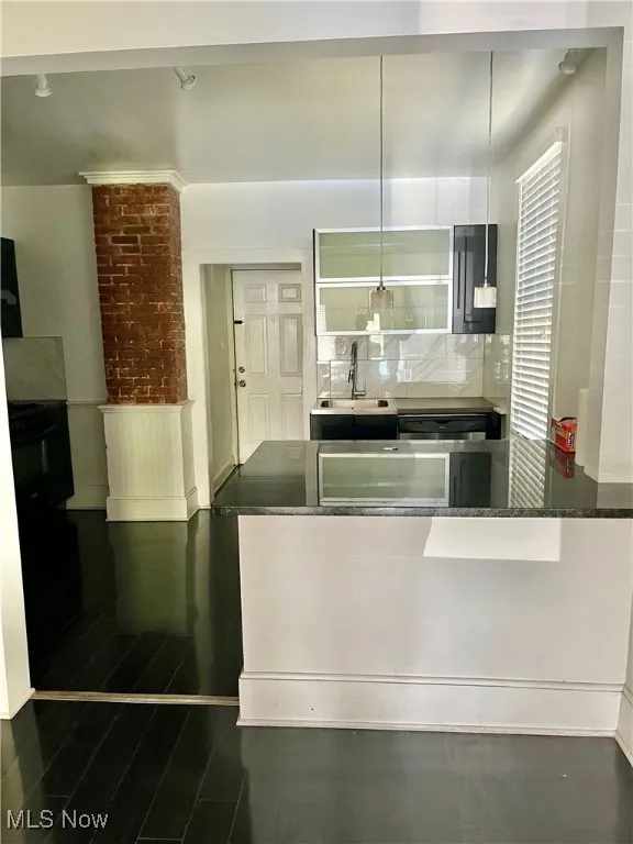 Kitchen with a peninsula, dark stone countertops, tasteful backsplash, pendant lighting, and a breakfast bar