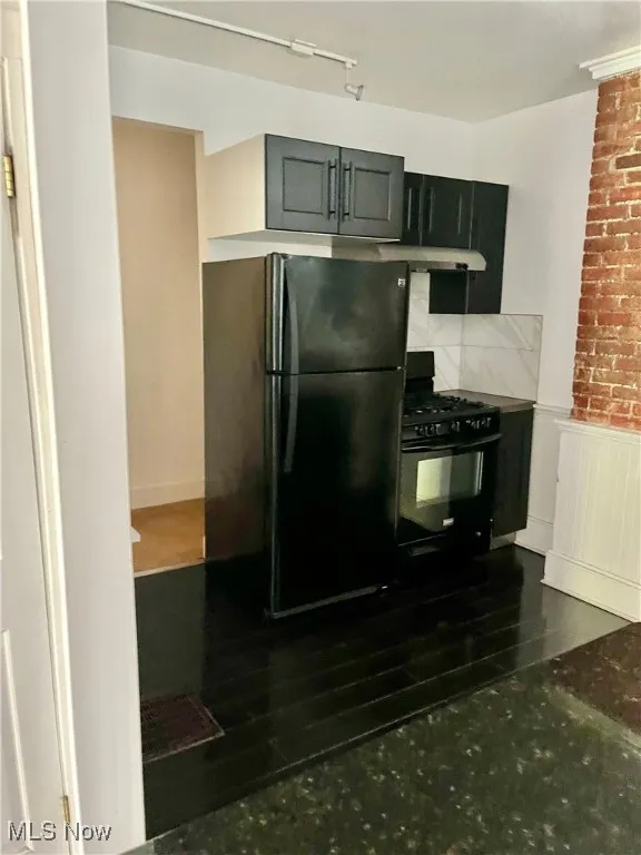 Kitchen with black appliances, gray cabinetry, wainscoting, dark cabinetry, and under cabinet range hood