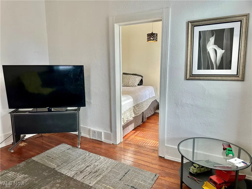 Bedroom with a textured wall and hardwood / wood-style flooring