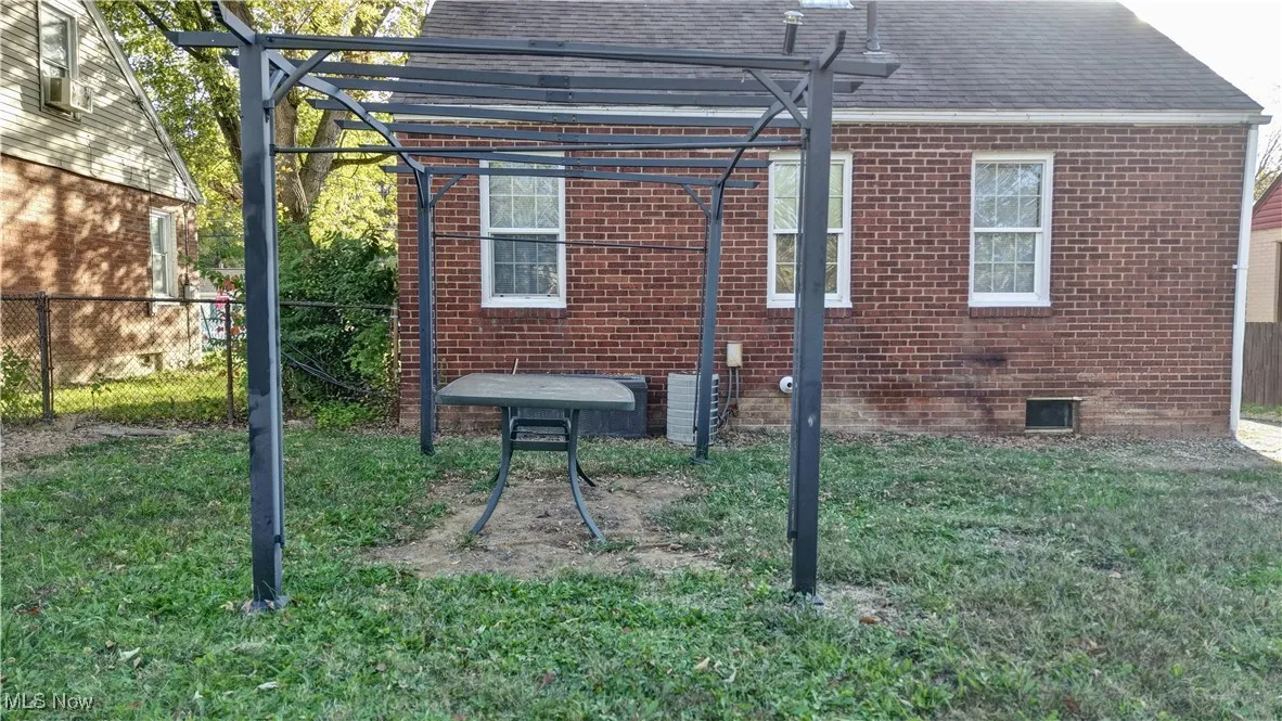 View of home's exterior with brick siding, a shingled roof, crawl space, and a pergola