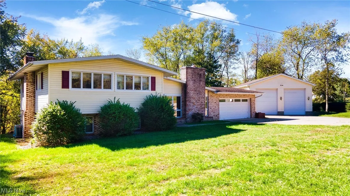 View of front of house featuring a chimney, brick siding, a front yard, and driveway