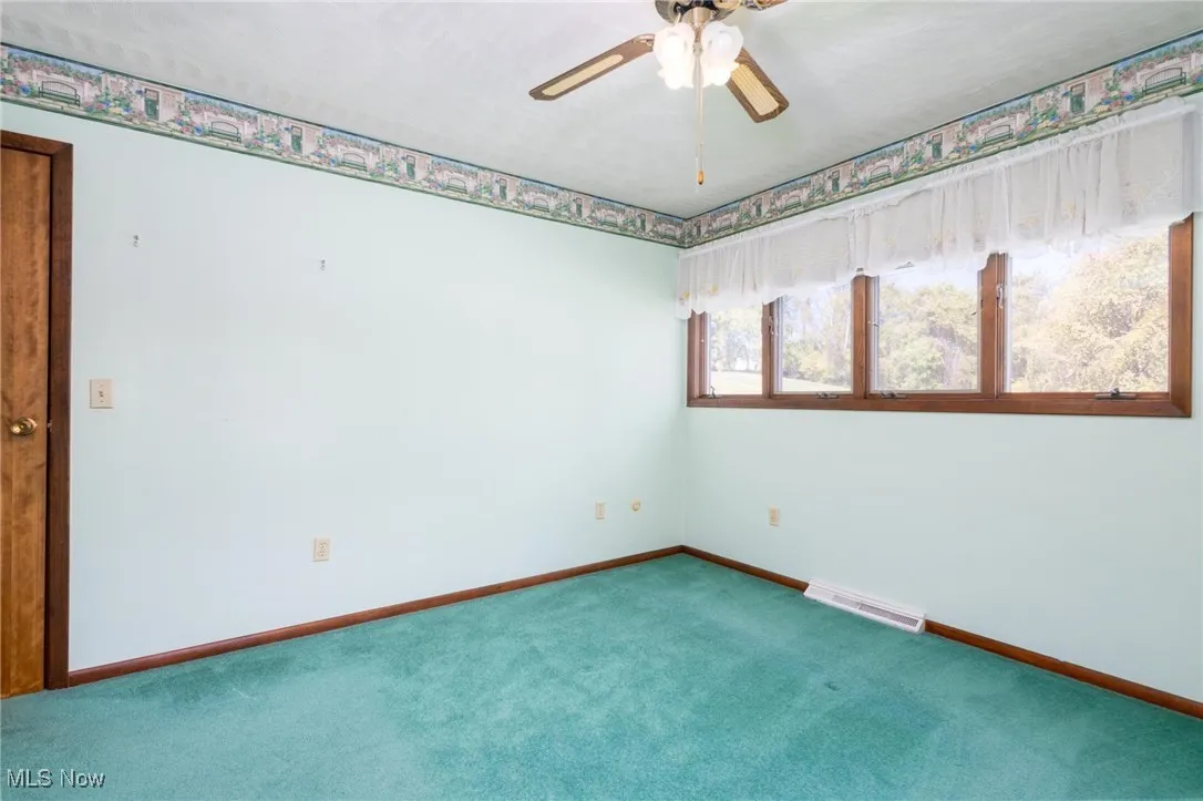 Carpeted spare room featuring baseboards and a ceiling fan