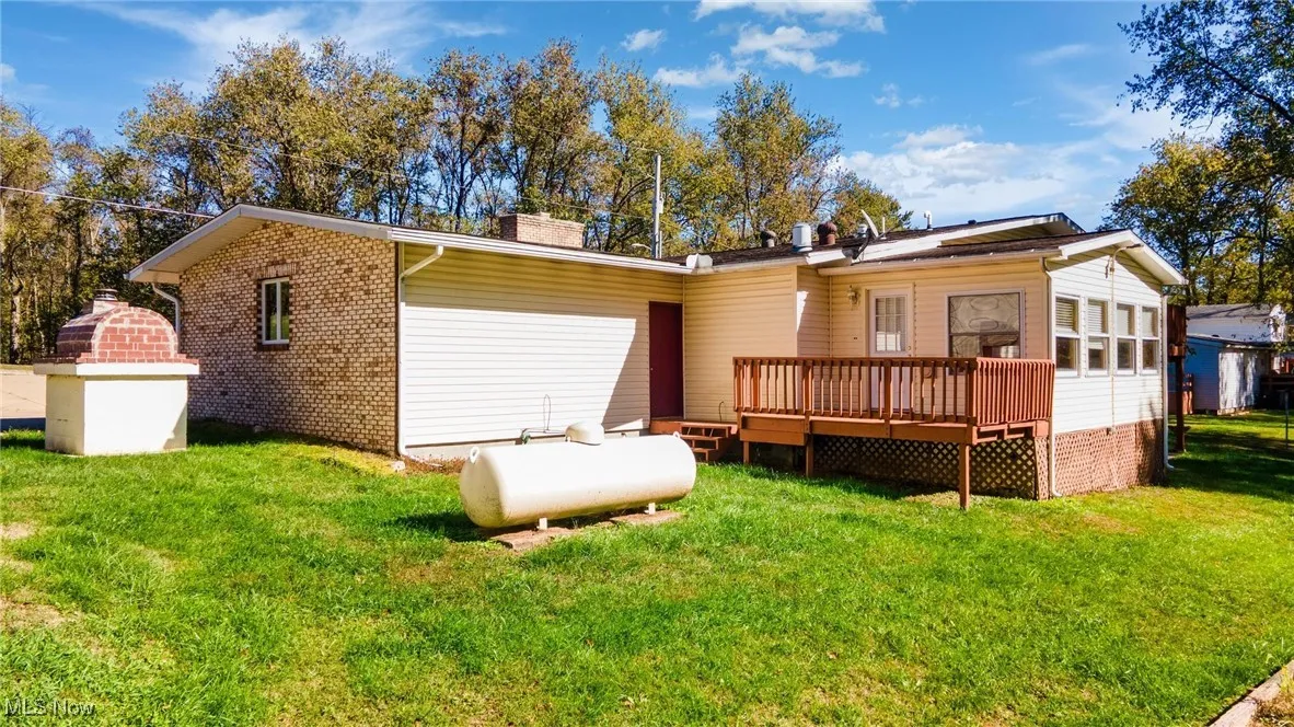 Back of property with a lawn, a deck, and a chimney