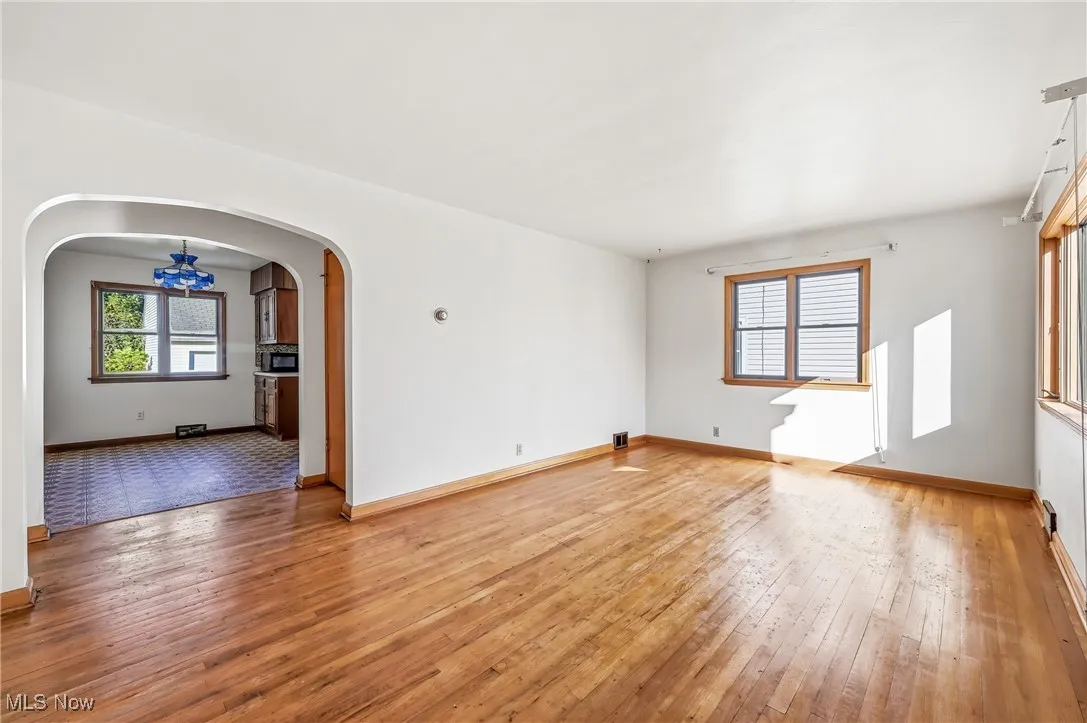 Spare room featuring light wood-style floors, arched walkways, and healthy amount of natural light