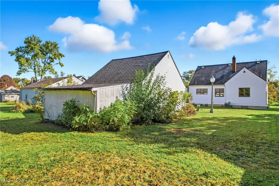 View of back of home and garage with a lawn