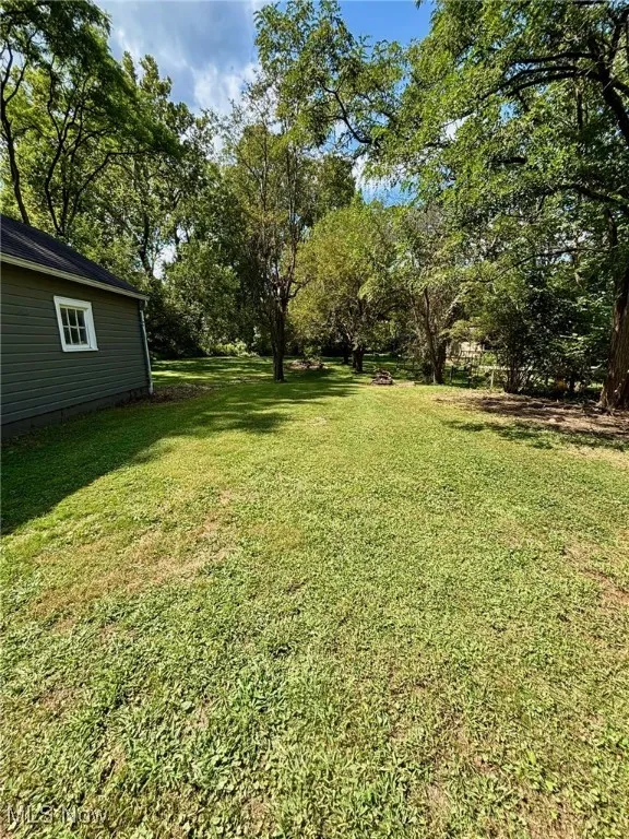 View of green lawn with view of wooded area