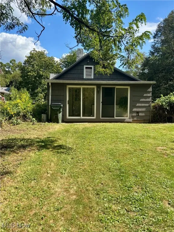 Rear view of house with a yard, a chimney, and an outbuilding