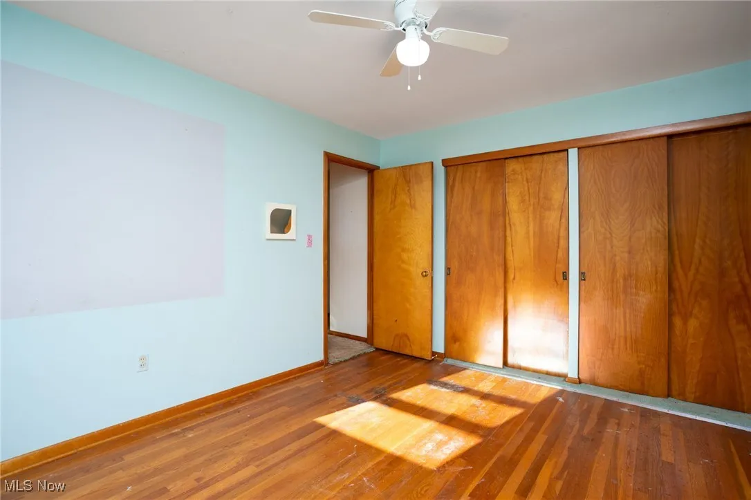 Unfurnished bedroom featuring wood-type flooring, a closet, and a ceiling fan