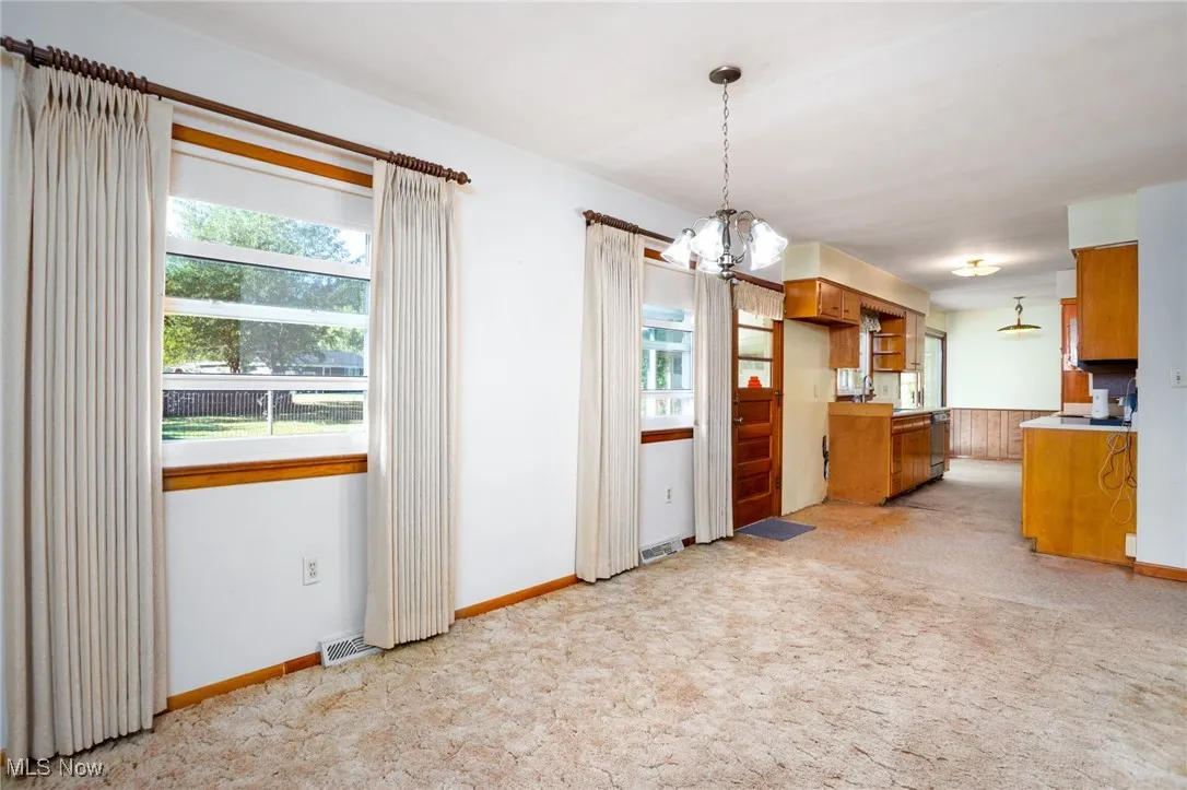 Kitchen featuring brown cabinets, light countertops, a chandelier, and pendant lighting