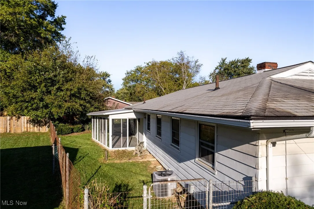 Rear view of house with a sunroom, a chimney, and roof with shingles