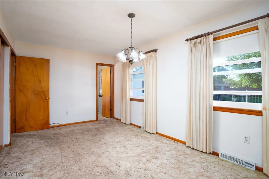 Unfurnished dining area with a chandelier and light carpet