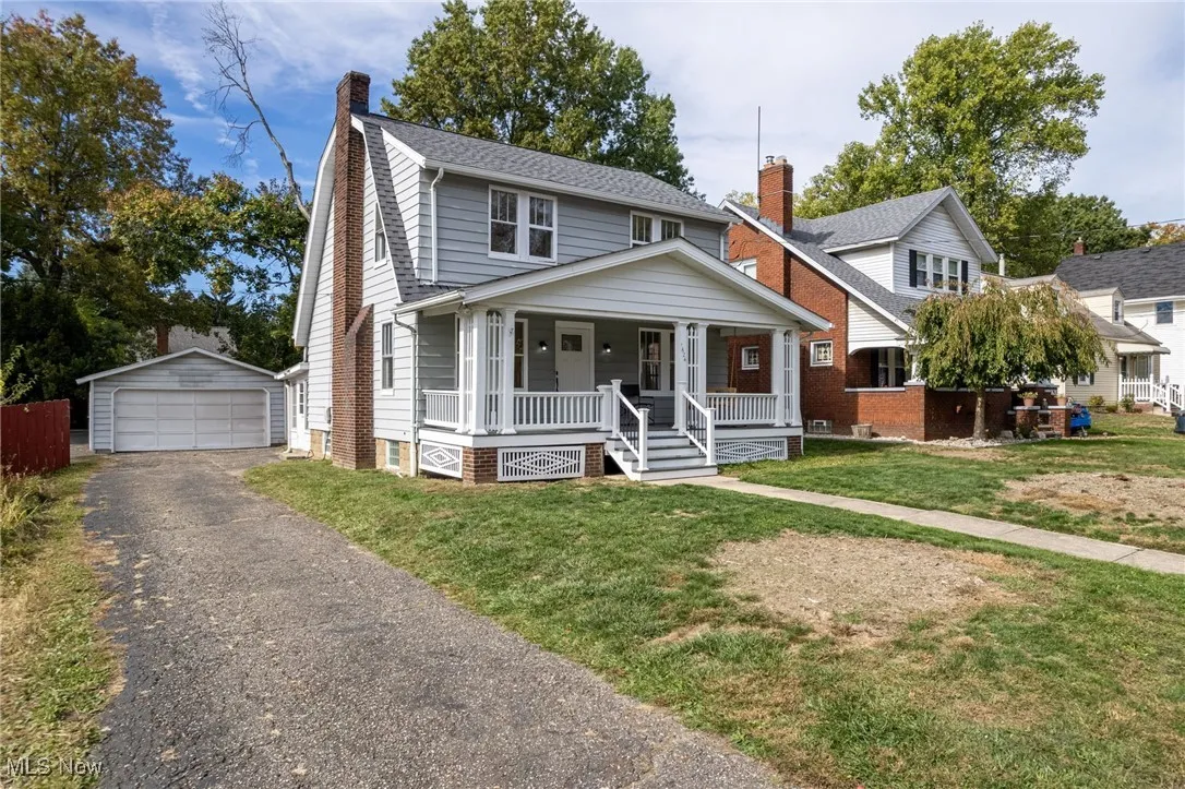 View of front of property with a porch, an outdoor structure, a garage, a chimney, and a front lawn