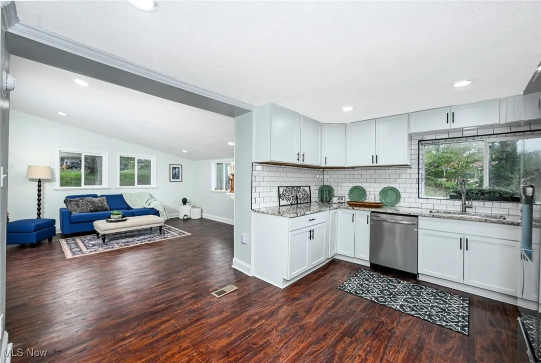 Kitchen featuring light stone countertops, vaulted ceiling, stainless steel appliances, recessed lighting, and decorative backsplash