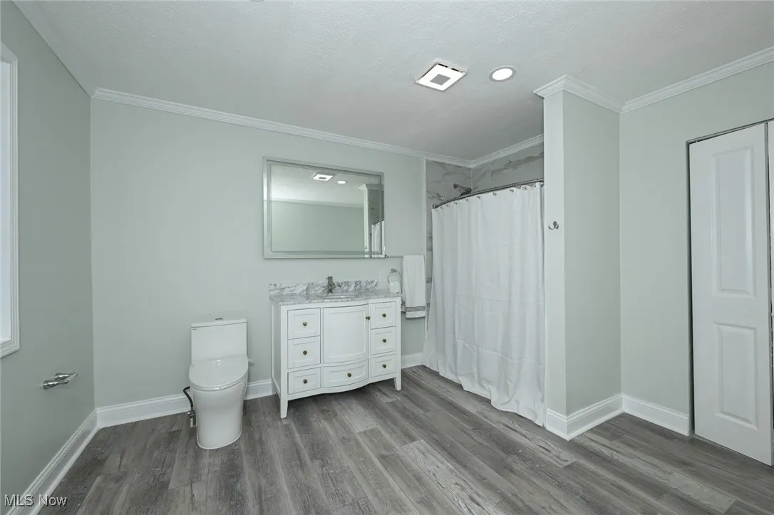 Full bath with ornamental molding, vanity, dark wood finished floors, a shower stall, and recessed lighting