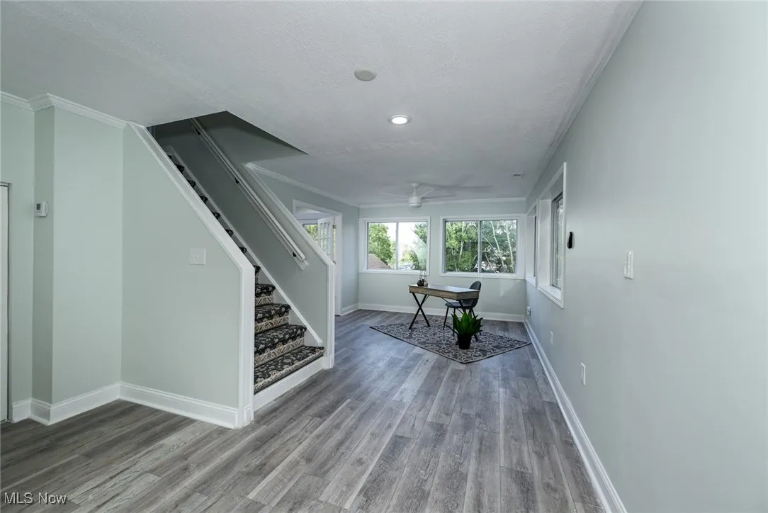 Living area featuring wood finished floors, stairway, ornamental molding, a textured ceiling, and a ceiling fan