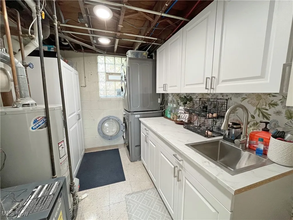 Washroom with stacked washer and clothes dryer and water heater
