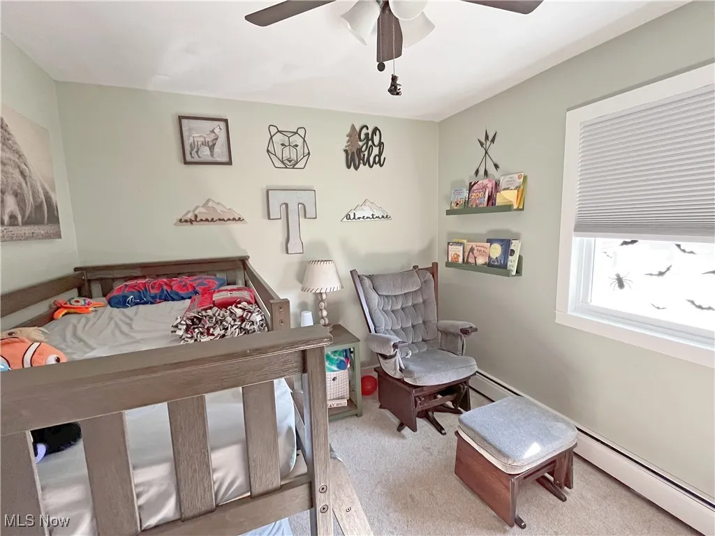 Bedroom with light carpet, a baseboard heating unit, and ceiling fan