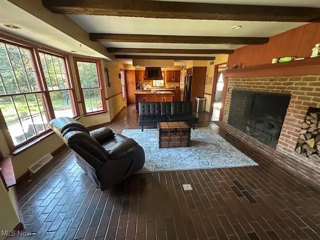 Living area with brick flooring, beamed ceiling, and a brick fireplace