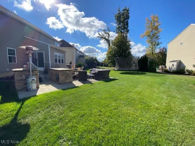 View of green lawn featuring a patio area, a trampoline, and outdoor lounge area