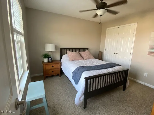 Carpeted bedroom featuring a ceiling fan and a closet