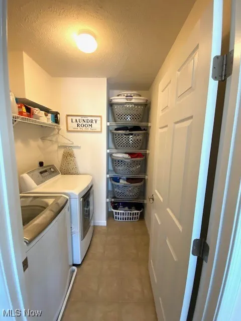 Washroom with a textured ceiling and separate washer and dryer