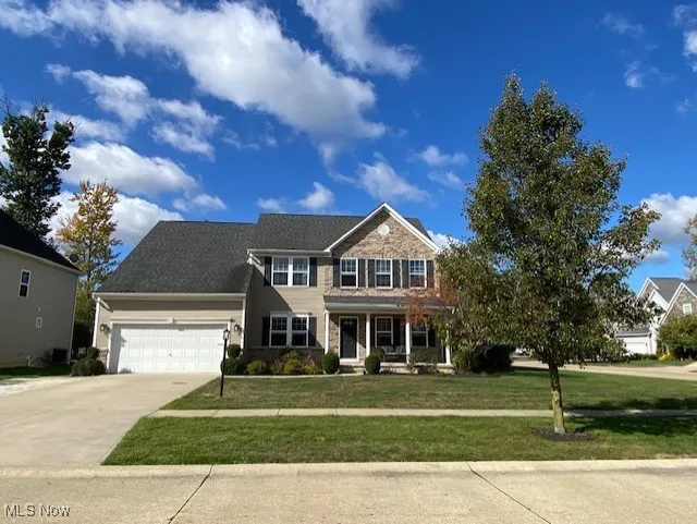 View of front of home with covered porch, a front yard, concrete driveway, and an attached garage