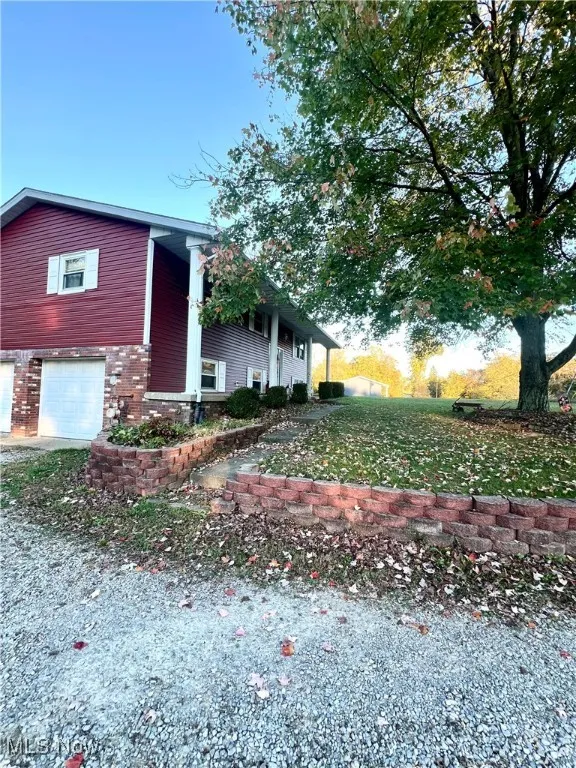 View of front facade with an attached garage, brick siding, covered porch, and driveway