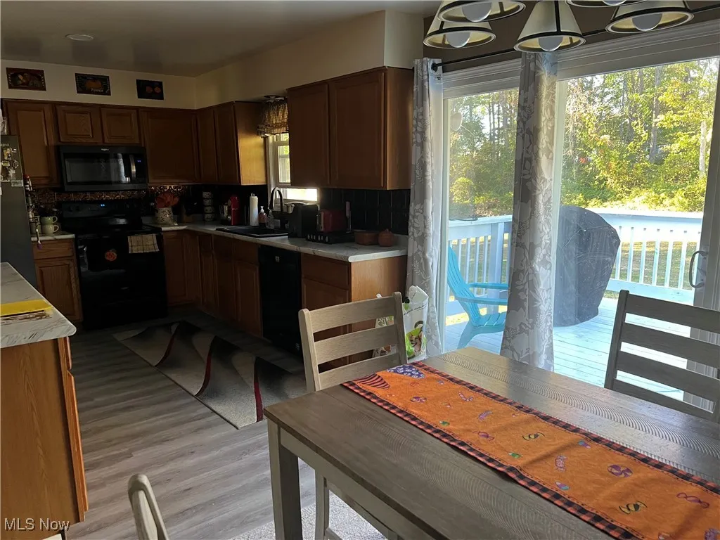 Kitchen with plenty of natural light, light countertops, black stainless appliances, and light wood-style flooring