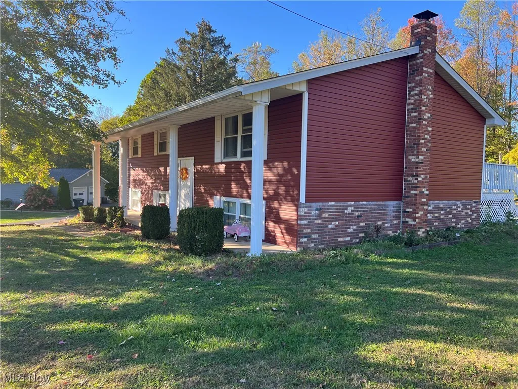 View of front facade featuring a chimney and a front lawn