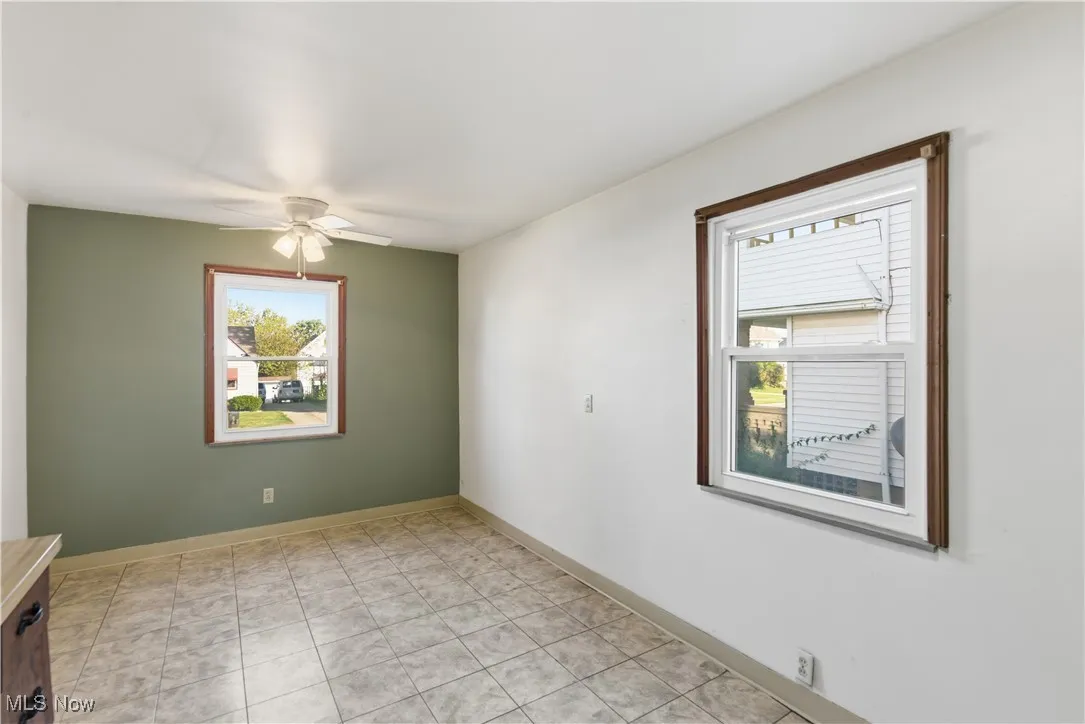 Spare room with healthy amount of natural light, light tile patterned flooring, and ceiling fan