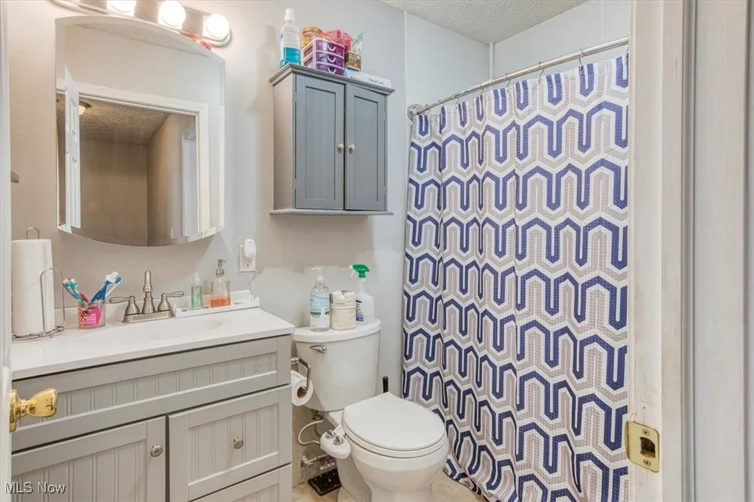 Full bathroom featuring vanity, a shower with shower curtain, and a textured ceiling