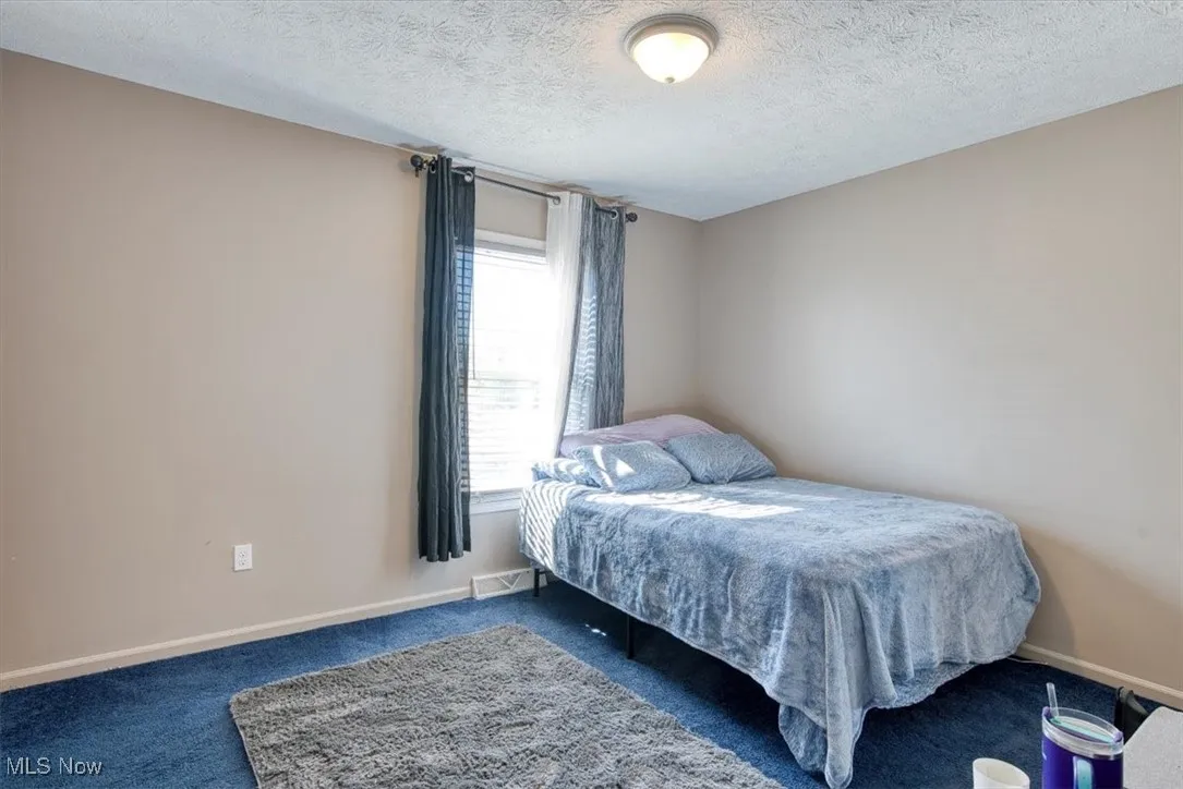 Carpeted bedroom with baseboards and a textured ceiling