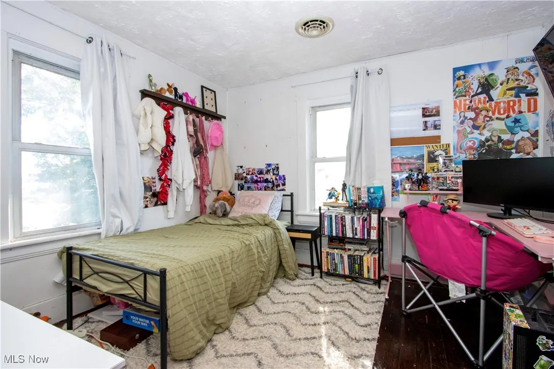 Bedroom with light wood-style flooring, a textured ceiling, and a desk