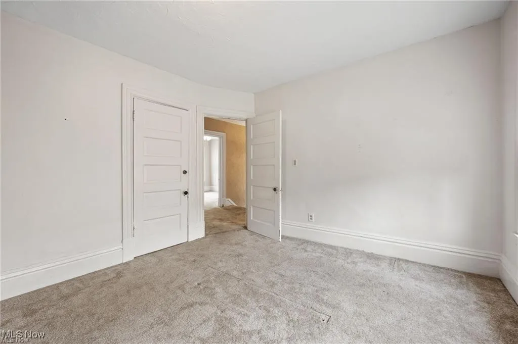 Carpeted spare room featuring baseboards