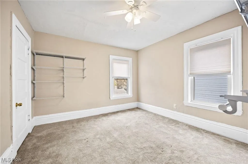 Empty room with light carpet and ceiling fan