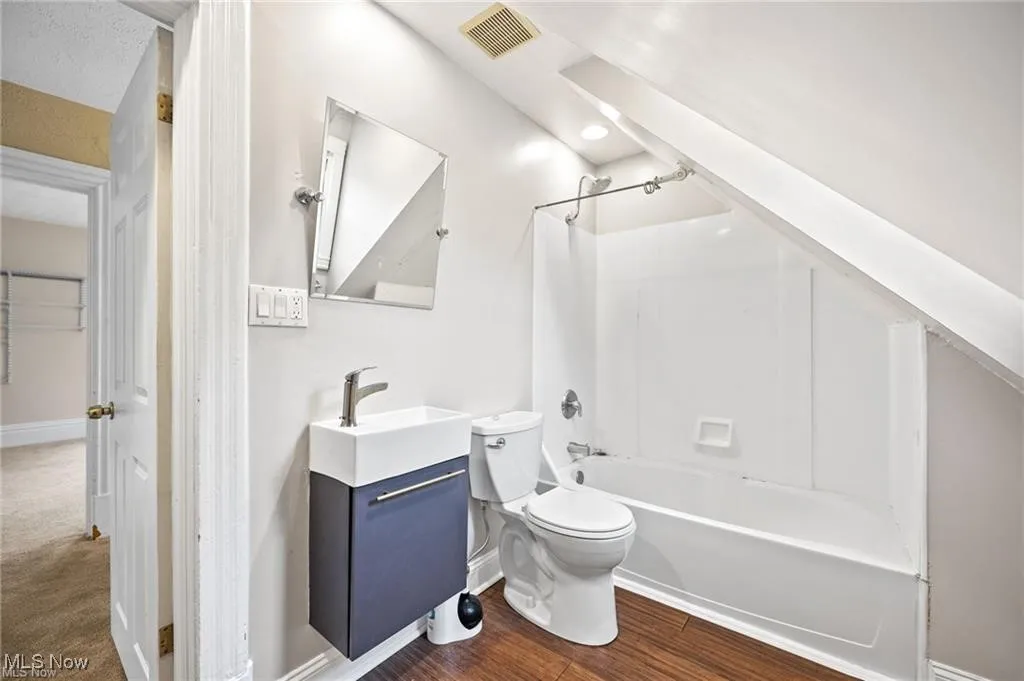 Bathroom featuring vanity, shower / tub combination, and wood finished floors