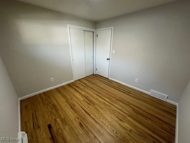 Unfurnished bedroom featuring wood finished floors and a closet