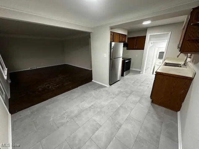 Kitchen featuring appliances with stainless steel finishes, light countertops, dark brown cabinetry, and open floor plan