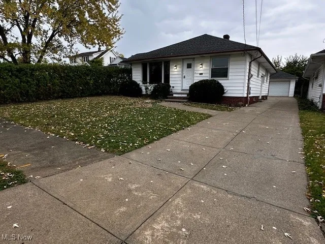Bungalow with a front yard, an outdoor structure, and a detached garage