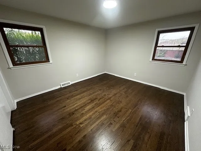 Empty room with dark wood-style floors and baseboards