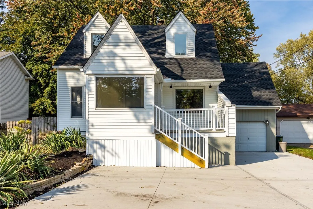 Cape cod house featuring roof with shingles, a garage, concrete driveway, and stairs