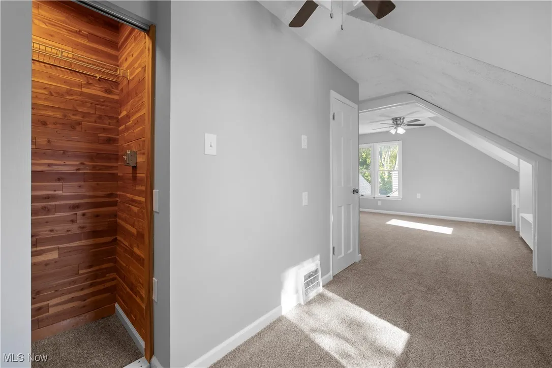 Bonus room featuring carpet floors, vaulted ceiling, and wood walls